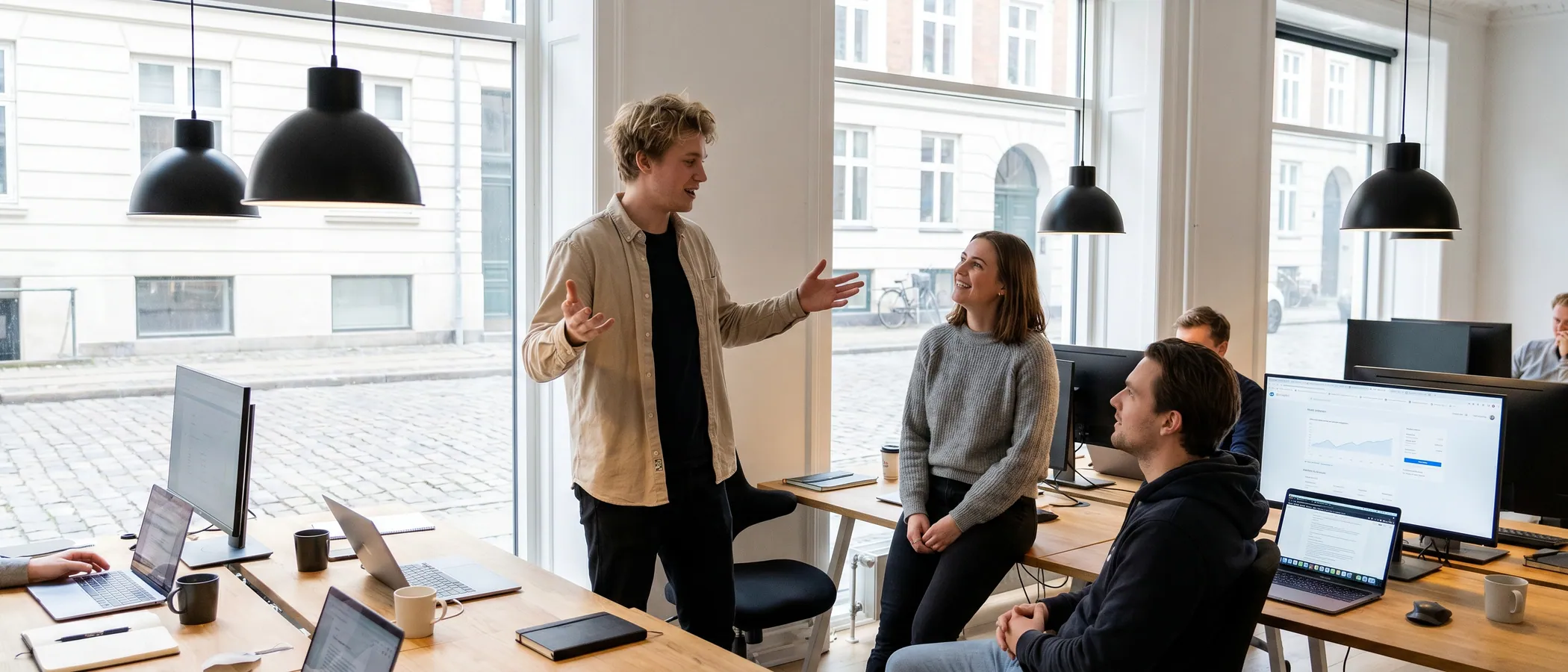 Tre kolleger på et marketingbureau kigger sammen på en laptop med Google Ads-resultater