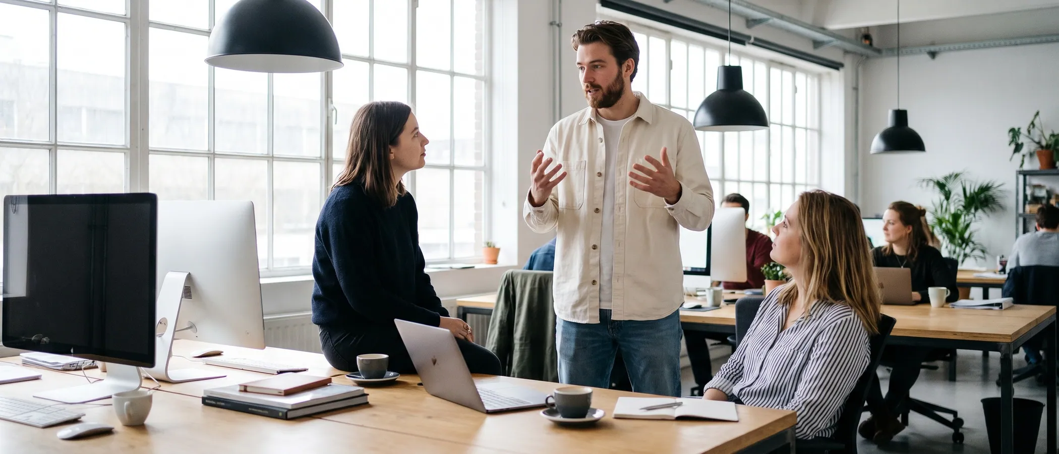Drie collega's bij een marketingbureau bekijken samen Google Ads resultaten op een laptop