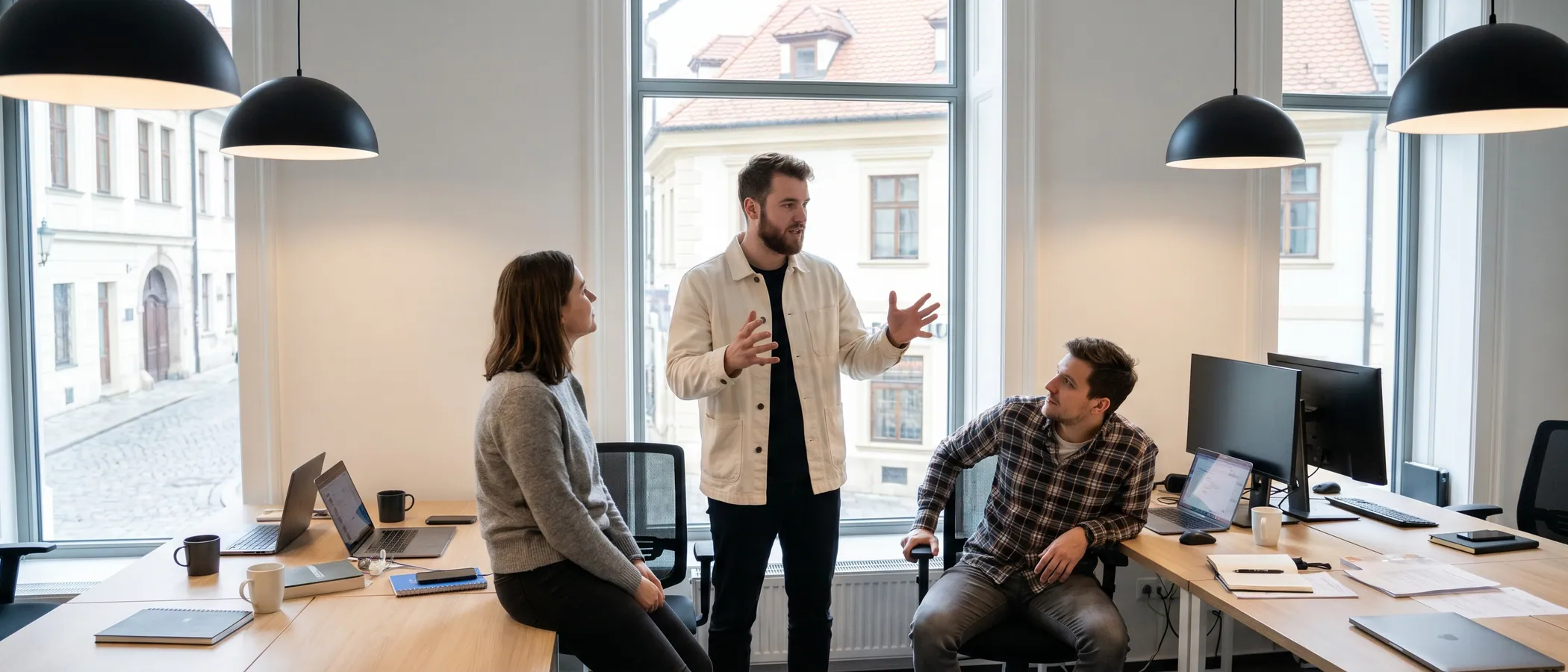 Traja kolegovia v marketingovej agentúre spoločne prezerajú Google Ads kampane na jednom laptope